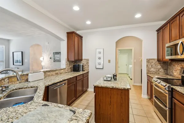 a large kitchen with stainless steel appliances granite countertop a sink and wooden cabinets
