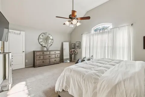 a spacious bedroom with a bed a chandelier and windows