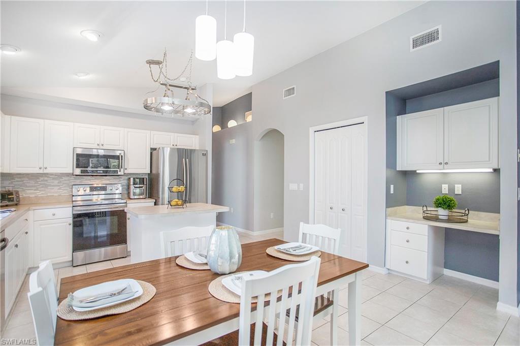 21722 Windham Run Estero, FL 33928 - Photo 11 of 40 a kitchen with stainless steel appliances kitchen island granite countertop a table and chairs in it