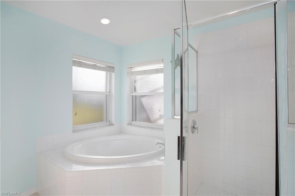 21722 Windham Run Estero, FL 33928 - Photo 15 of 40 a bathroom with a bathtub a shower and a window