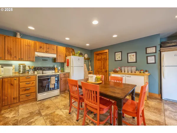 a kitchen with stainless steel appliances kitchen island granite countertop a table chairs sink and cabinets