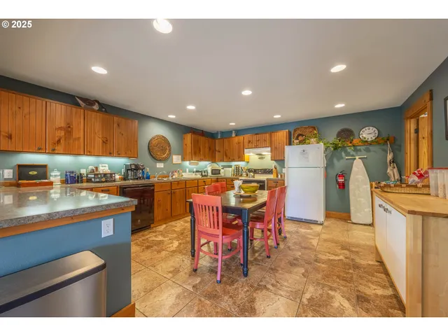 a kitchen with stainless steel appliances kitchen island granite countertop a table chairs sink and cabinets