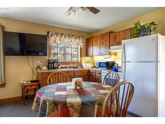 a kitchen with stainless steel appliances granite countertop a refrigerator a sink a stove a dining table and chairs