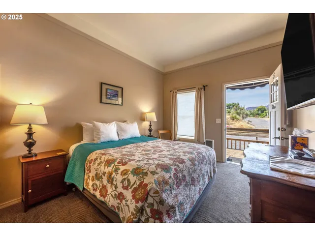 a bedroom with a bed and a flat tv screen on dresser