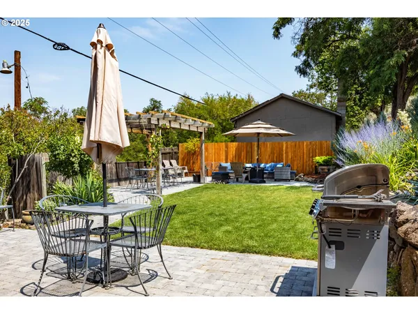 a view of a table and chairs under an umbrella in backyard