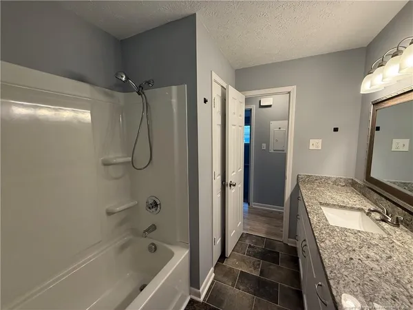 a bathroom with a granite countertop sink a toilet and shower