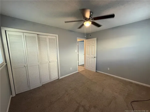 an empty room with closet and a chandelier fan
