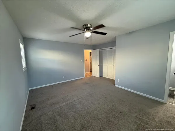 a view of an empty room and a ceiling fan & window