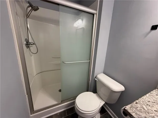a white toilet sitting next to a shower