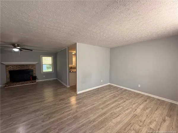 an empty room with wooden floor fireplace and staircase