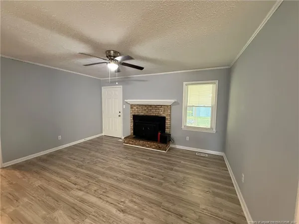 a view of an empty room with a fireplace and a window