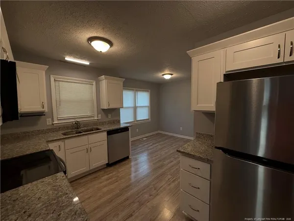 a kitchen with stainless steel appliances granite countertop a refrigerator a stove and a sink