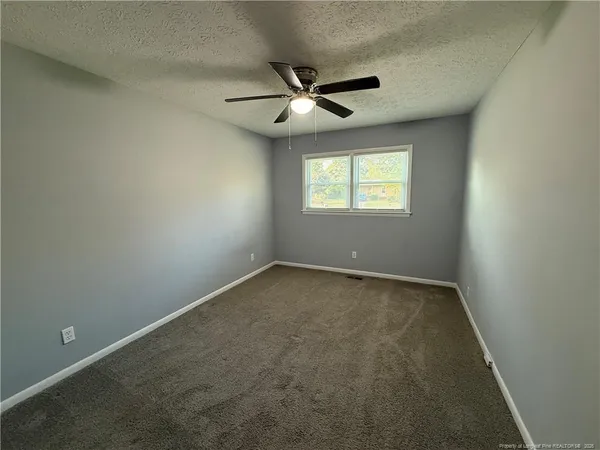 an empty room with a window and a fan