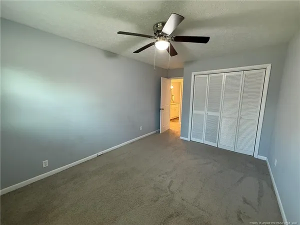 an empty room with a ceiling fan and carpet