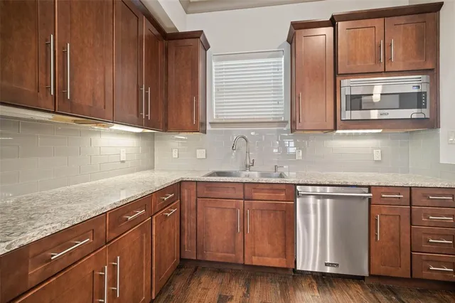a kitchen with granite countertop wooden cabinets a sink and dishwasher