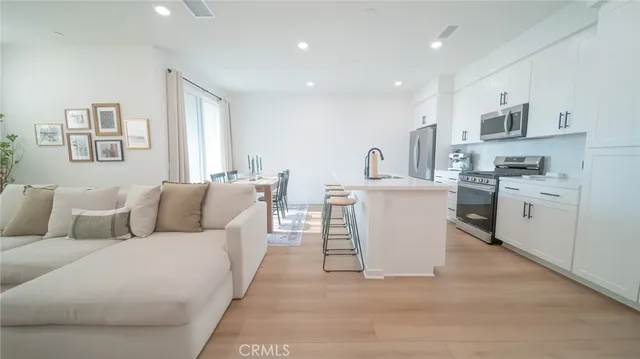 a living room with stainless steel appliances kitchen island granite countertop a couch and cabinets