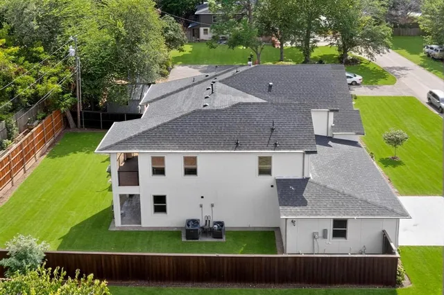 a backyard of a house with plants and large tree