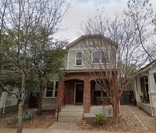 a front view of a house with a tree