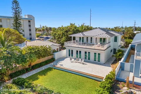 a white house with a large pool and lawn chairs under an umbrella