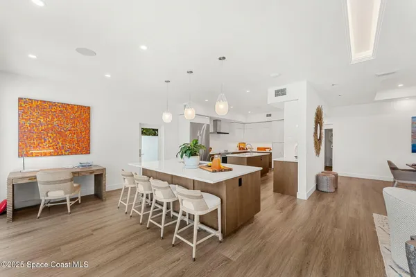 a kitchen with stainless steel appliances a dining table chairs and wooden floor
