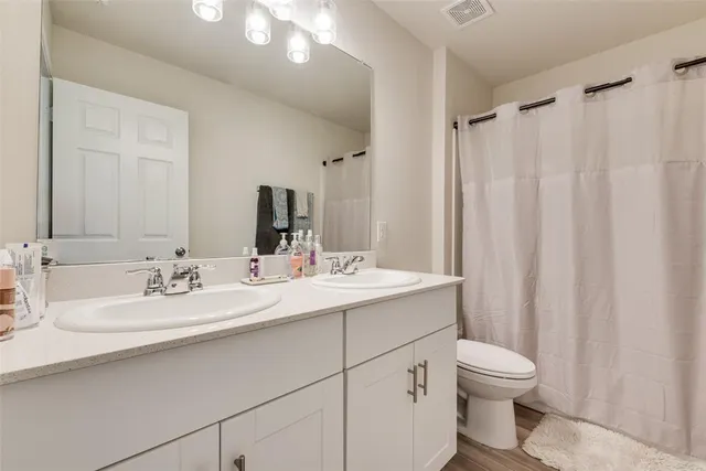 a bathroom with a double vanity sink toilet and a mirror