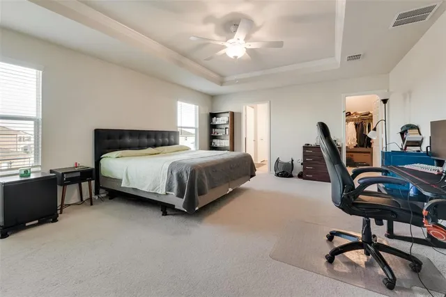 a bedroom with a bed a desk and chair with the potted plants
