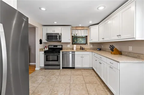 a kitchen with granite countertop a refrigerator and a stove top oven