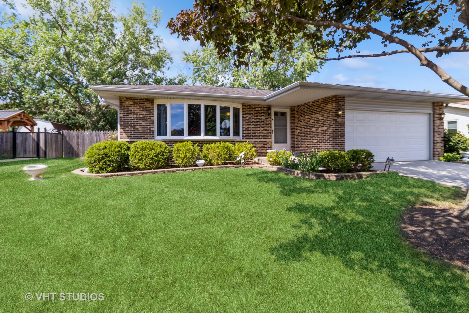 a front view of a house with a yard and large tree