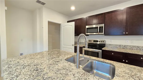 a kitchen with stainless steel appliances granite countertop a sink stove and microwave