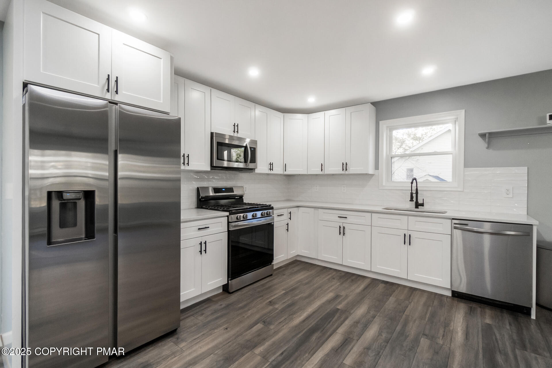411 Alter Avenue Pocono Summit, PA 18346 - Photo 3 of 29 a kitchen with stainless steel appliances granite countertop a refrigerator a sink dishwasher a stove and white cabinets with wooden floor