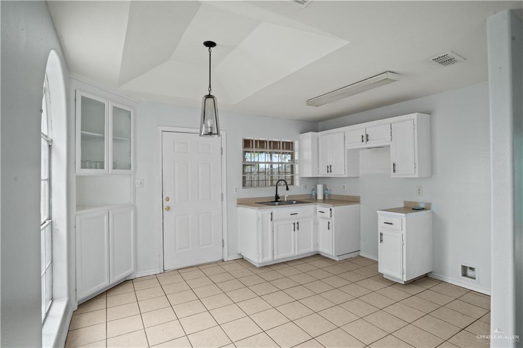 6402 South Mars Lane Pharr, TX 78577 - Photo 4 of 17 a kitchen with white cabinets a sink dishwasher and a stove next to a window