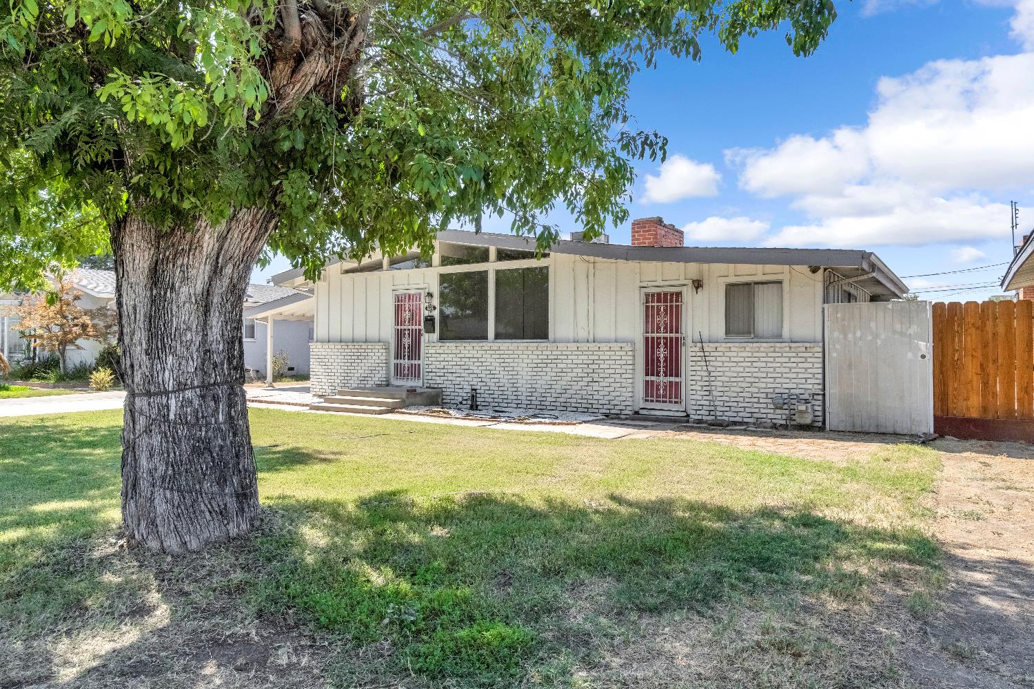 835 I Street Parlier, CA 93648 - Photo 3 of 27 a front view of house with yard and trees in the background