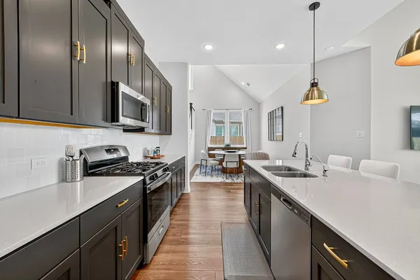 a kitchen with kitchen island granite countertop a sink a counter space cabinets and stainless steel appliances