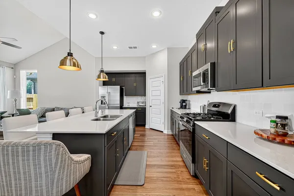 a kitchen with stainless steel appliances granite countertop a stove a sink and a microwave