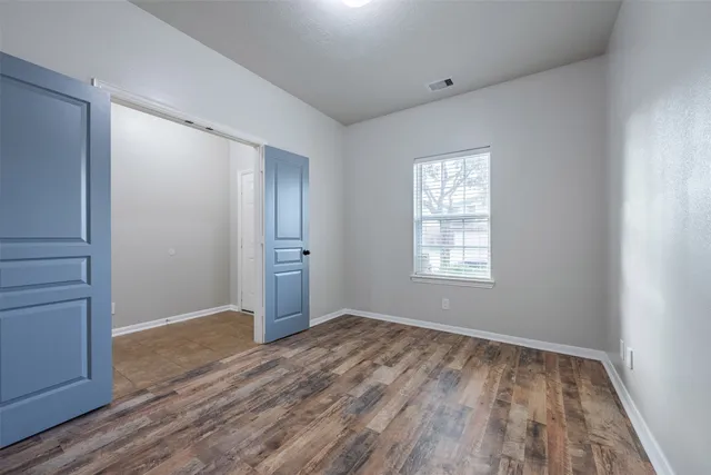 a view of an empty room with wooden floor and a window