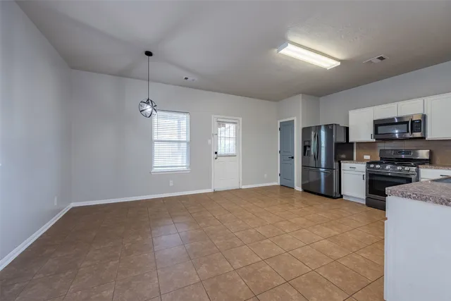 a view of a kitchen with stainless steel appliances a refrigerator and a stove top oven