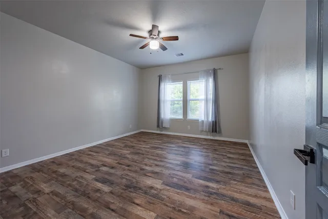a view of empty room with wooden floor and fan