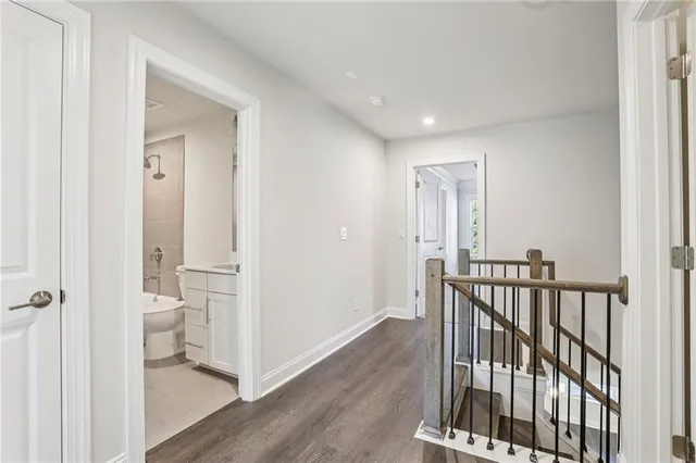 a view of a hallway with wooden floor and a bathroom