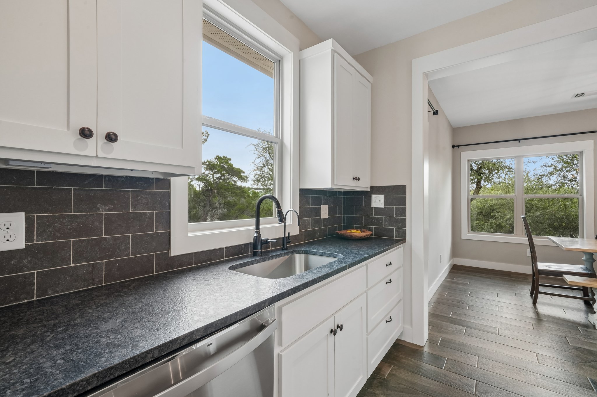 190 Magnolia Meadow Spring Branch, TX 78070 - Photo 8 of 29 A well-appointed kitchen features dark countertops, white cabinetry, and a window overlooking lush greenery.