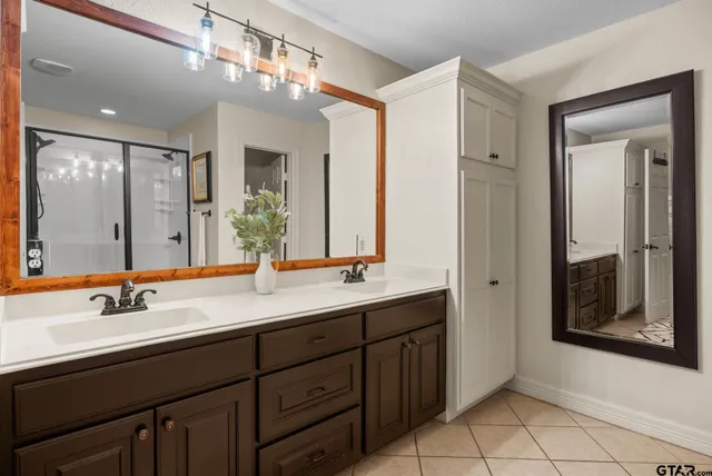 a bathroom with double vanity sinks a vanity a mirror and a shower