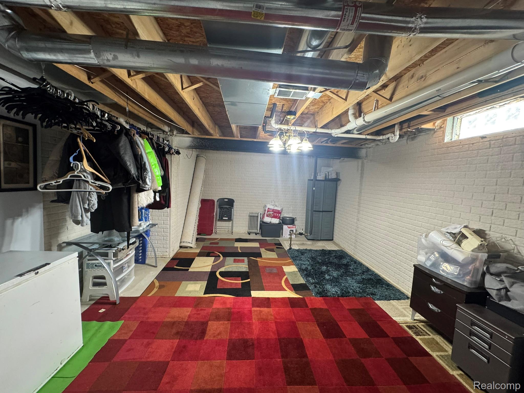 324 Cherry Lane Inkster, MI 48141 - Photo 26 of 28 Finished basement space featuring exposed ceiling joists, white-painted brick walls, and two small windows providing natural light