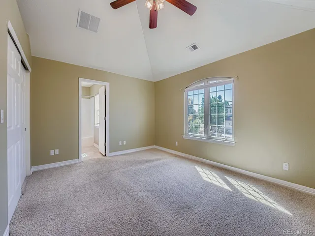 a view of an empty room with window and chandelier fan