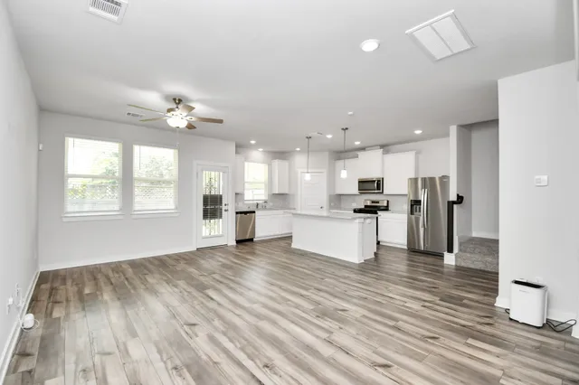 a view of kitchen with kitchen island wooden floor center island and stainless steel appliances