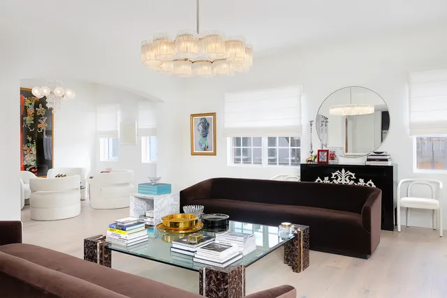 a living room with furniture kitchen view and a chandelier