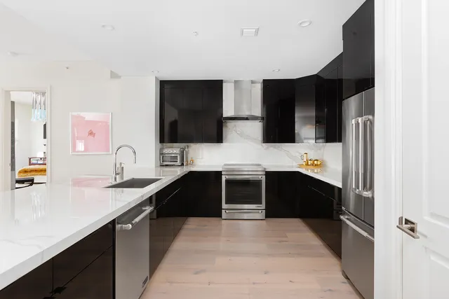 a large kitchen with a sink and a stove top oven with wooden floor