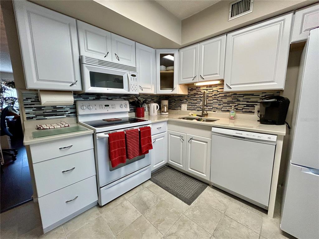 2260 Costa Rican Drive, Unit 50 Clearwater, FL 33763 - Photo 11 of 48 a kitchen with white cabinets stainless steel appliances and sink