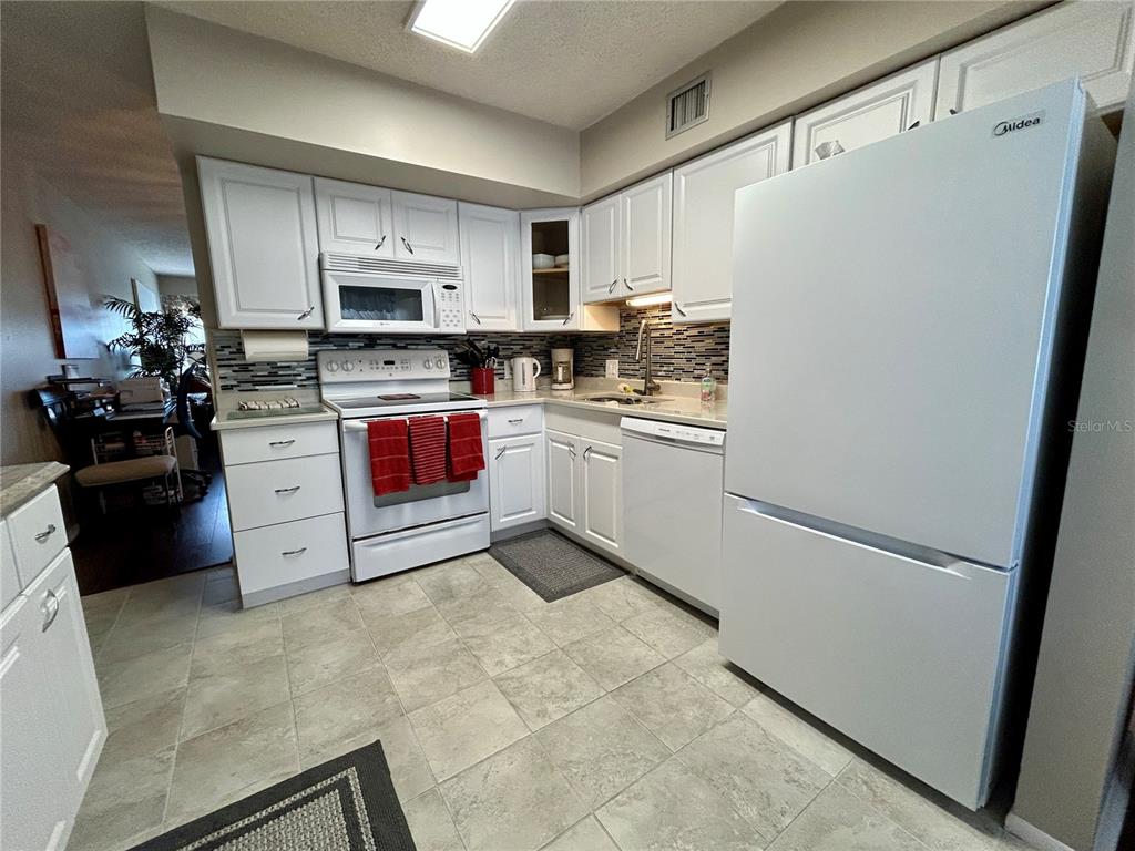 2260 Costa Rican Drive, Unit 50 Clearwater, FL 33763 - Photo 8 of 48 a kitchen with white cabinets and white appliances