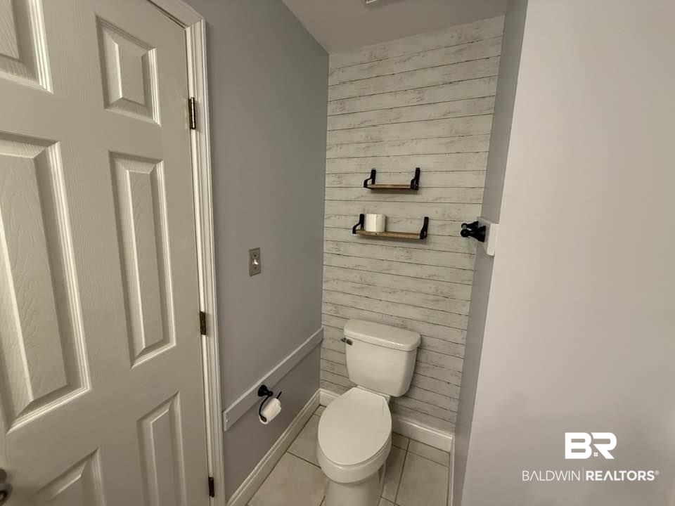 10428 South Side Loop Fairhope, AL 36532 - Photo 27 of 28 Bathroom with toilet, wood walls, tile patterned flooring, and baseboards