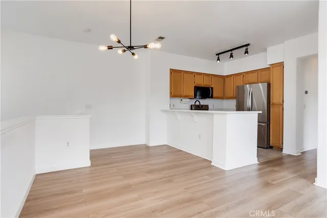 a view of a kitchen with wooden floor a sink a refrigerator and window