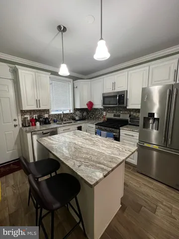 a kitchen with kitchen island granite countertop a stove a sink a refrigerator wooden floor and a window